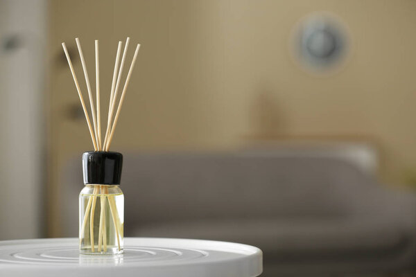 Aromatic reed air freshener on table against blurred background