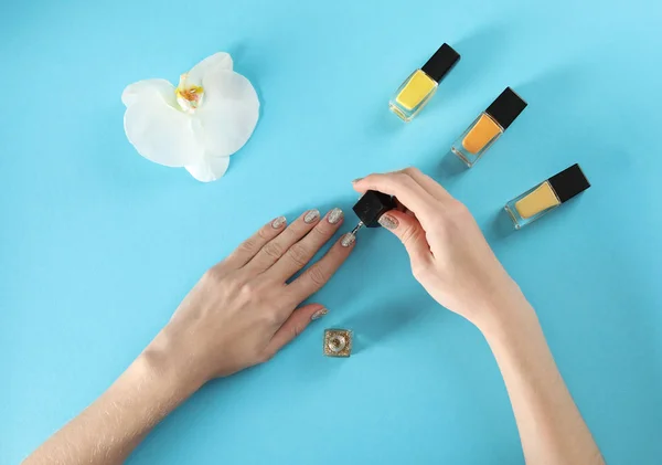 Mujer aplicando esmalte de uñas sobre fondo de color, vista superior — Foto de Stock