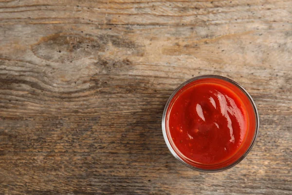 Verre de sauce tomate savoureuse sur table en bois, vue sur le dessus. Espace pour le texte — Photo