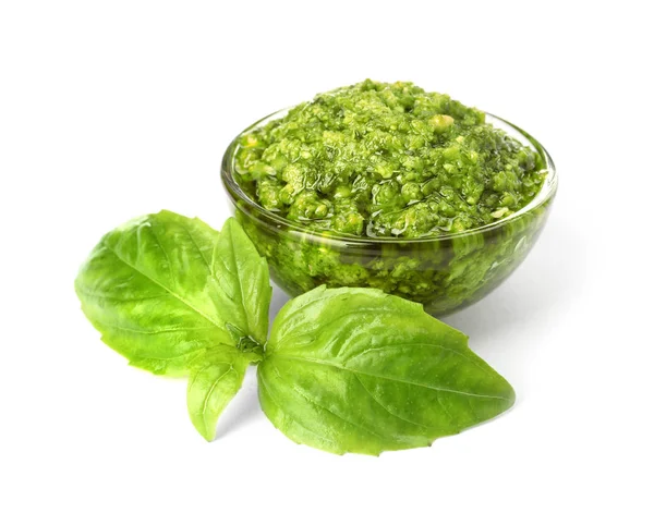 Ciotola di gustosa salsa al pesto con foglie di basilico isolate su bianco — Foto Stock