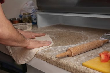 Masadaki pizza için hamur hazırlayan adam, yakın çekim. Fırın tarifi