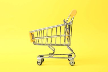 Renkli arka planda saplı boş alışveriş arabası