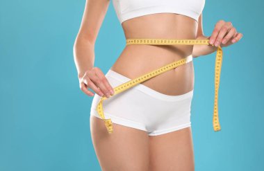 Renk arka plan üzerinde vücut ölçme iç çamaşırı pürüzsüz nazik bir cilde sahip ince genç kadın, closeup