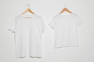 Beyaz arka planda boş tişörtler olan askılar. Tasarım için alay