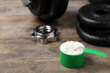 Ahşap masa üzerinde protein tozu ve halter parçaları ile Kepçe. Metin için alan