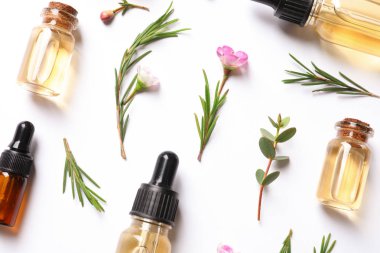 Beyaz arka planda doğal çay ağacı yağı şişeleri ile düz yatıyordu kompozisyon