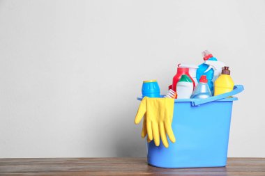 Hafif arka plana karşı masada farklı temizlik ürünleri ile Plastik kova. Metin için alan