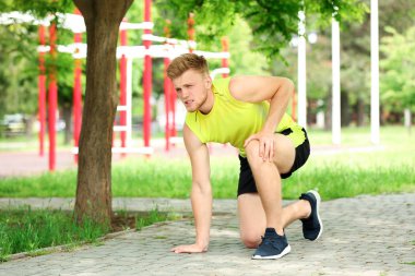 Genç adam parkta diz ağrısı çekiyor.