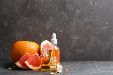 Gri masada uçucu yağ ve greyfurt şişeleri, metin için alan