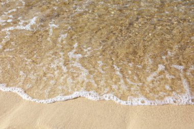 Güneşli bir günde deniz suyu ve plaj kumu manzarası