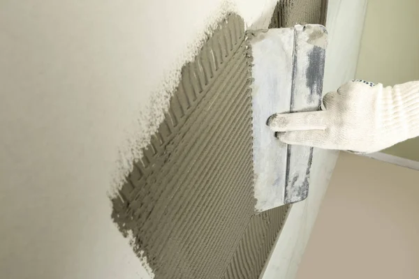 Closeup de trabalhador espalhando concreto na parede com espátula, espaço para texto. Instalação da telha — Fotografia de Stock