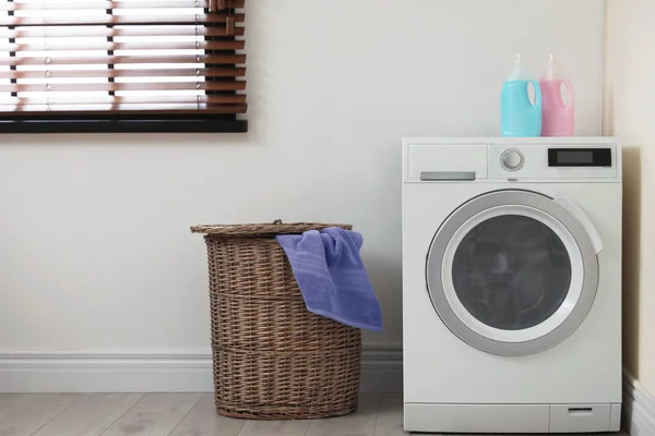 Máquina de lavar roupa moderna e cesta de lavanderia dentro de casa — Fotografia de Stock