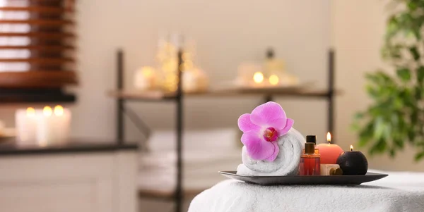 Komposition mit Handtuch, Kerzen und Ölen auf Massagetisch im Wellness-Salon. Raum für Text — Stockfoto
