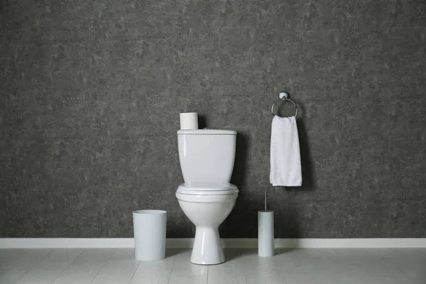 Простий інтер'єр ванної кімнати з новою унітазом біля сірої стіни — стокове фото