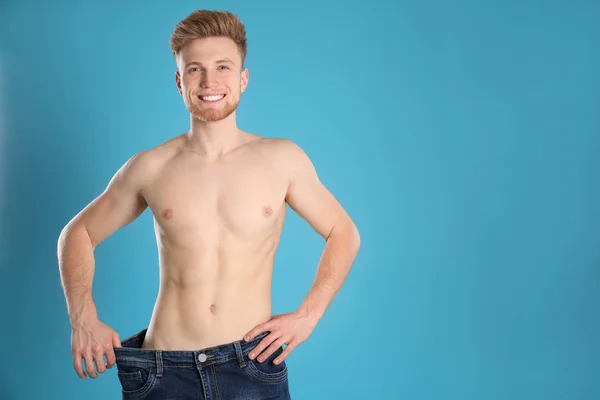 Hombre guapo en pantalones vaqueros de gran tamaño sobre fondo de color. Espacio para texto — Foto de Stock