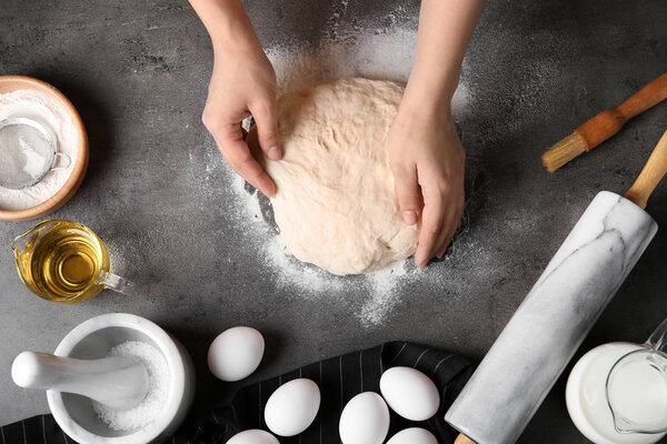 Female baker preparing bread dough at kitchen table, top view