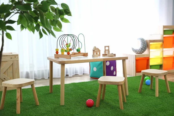 Stilvolles Spielzimmer-Interieur mit Spielzeug und modernen Holzmöbeln — Stockfoto