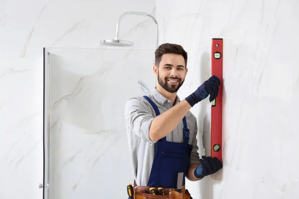 Handyman trabajando con el nivel del edificio en el baño. Herramientas de construcción profesionales — Foto de Stock