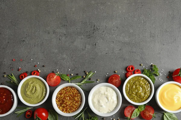 Cuencos con diferentes salsas e ingredientes sobre fondo gris, la puesta plana. Espacio para texto — Foto de Stock