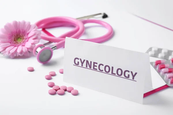 Kortti sanalla Gynekologia, pillerit, stetoskooppi ja kukka valkoisella taustalla — kuvapankkivalokuva