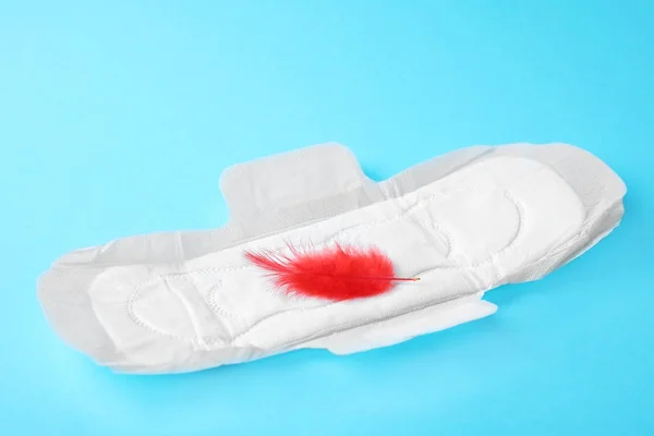 Menstrual pad dan bulu merah pada latar belakang warna. Pengobatan ginekologi — Stok Foto