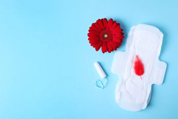 Différents produits d'hygiène féminine, plume rouge et fleur sur fond de couleur, pose plate avec espace pour le texte. Soins gynécologiques — Photo