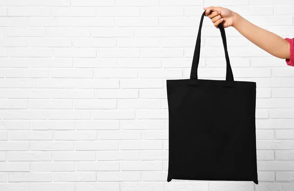 Mujer con elegante bolsa ecológica en blanco cerca de la pared de ladrillo, primer plano. Espacio para texto — Foto de Stock