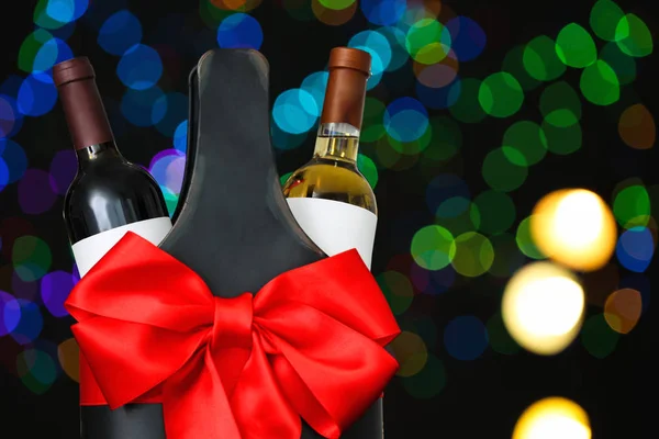 Festive package with bottles of wine against blurred lights, space for text. Bokeh effect