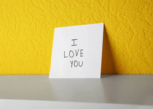 色の壁の棚にあなたを愛するテキストを持つ紙 — ストック写真