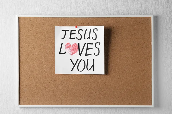 Пробковая доска с бумагой и письменным текстом Иисус любит вас на белом фоне — стоковое фото