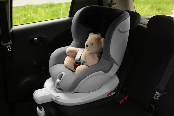 Osito de peluche en asiento de seguridad para niños dentro del coche. Prevención de peligros — Foto de Stock