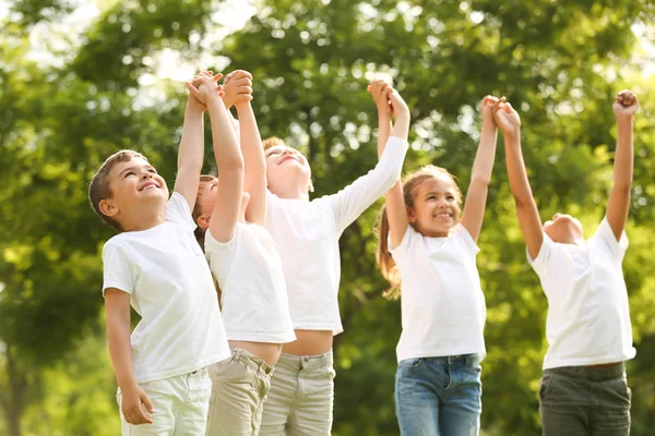 Ομάδα παιδιών που κρατάνε τα χέρια ψηλά στο πάρκο. Εθελοντική εργασία — Φωτογραφία Αρχείου