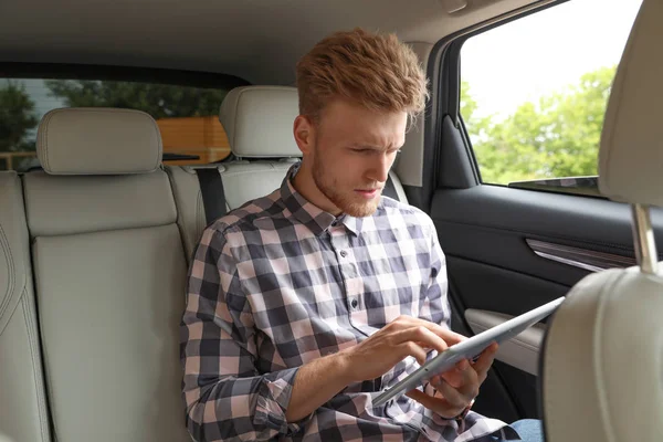고급 차에 태블릿을 사용 하는 매력적인 젊은 남자 — 스톡 사진
