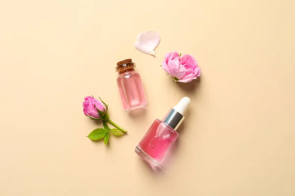 Flores frescas y botellas de aceite esencial de rosa sobre fondo de color, planas —  Fotos de Stock