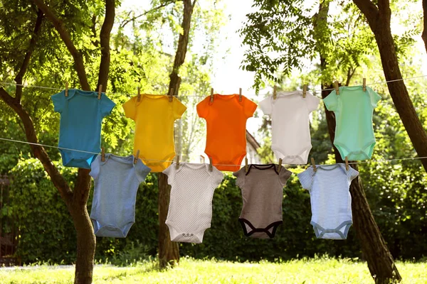 Colorido bebé onesies colgando en líneas de ropa fuera —  Fotos de Stock