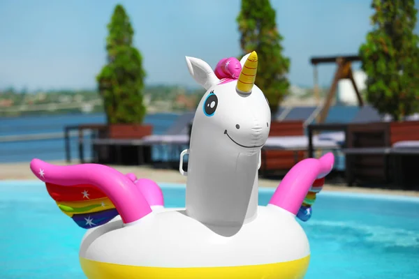 Funny inflatable unicorn ring floating in swimming pool on sunny day, outdoors