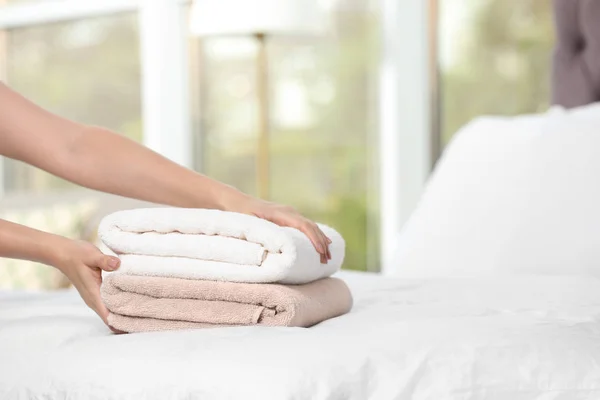 Woman putting soft clean towels onto bed, closeup. Space for text — Stock Photo, Image