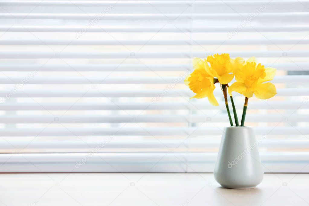 Window with blinds and beautiful bouquet on sill, space for text