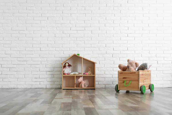 Almacenamiento de madera con juguetes cerca de la pared de ladrillo blanco en el interior de la habitación del bebé — Foto de Stock