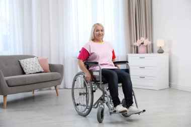 Evde tekerlekli sandalyede oturan Olgun kadın