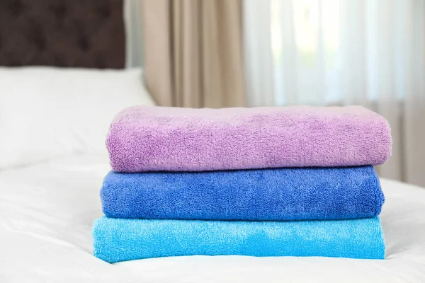 Different soft terry towels on bed in room — Stock Photo, Image
