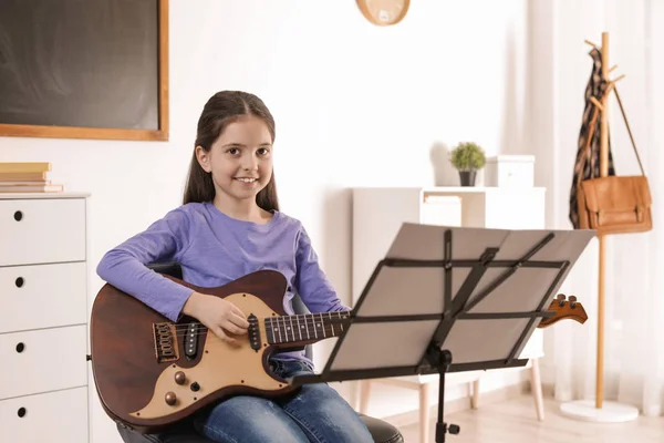 音楽のレッスンでギターを弾く小さな女の子。学習ノート — ストック写真