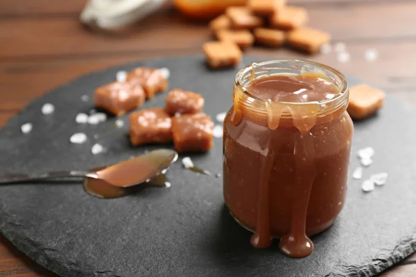 Placă de ardei cu borcan de sos caramel gustos pe masă de lemn. Spațiu pentru text — Fotografie, imagine de stoc