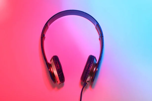 Fones de ouvido elegantes no fundo de cor, vista superior — Fotografia de Stock