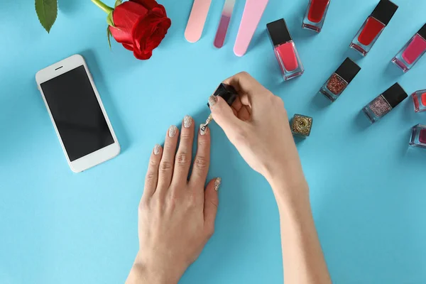 Woman applying nail polish on color background, top view — Stock Photo, Image