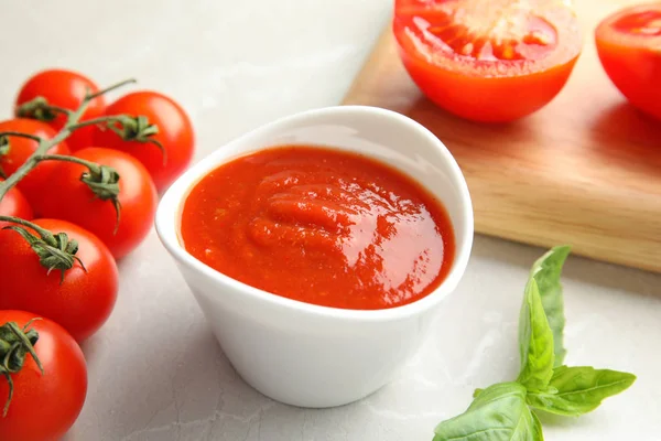 Komposition mit Schüssel Tomatensauce auf hellem Tisch — Stockfoto