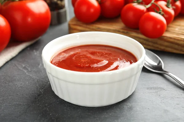 Komposition mit Schüssel Tomatensauce auf grauem Tisch — Stockfoto