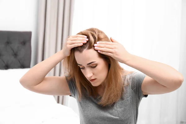 Молодая женщина с проблемой выпадения волос в спальне — стоковое фото