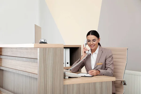 Recepcionista falando por telefone na mesa do hotel moderno — Fotografia de Stock