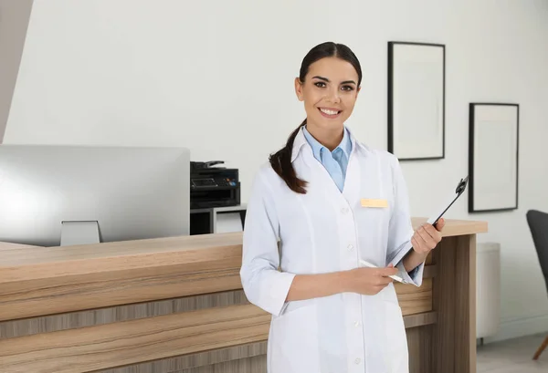 Portret van receptioniste met Klembord bij Bureau in moderne kliniek — Stockfoto